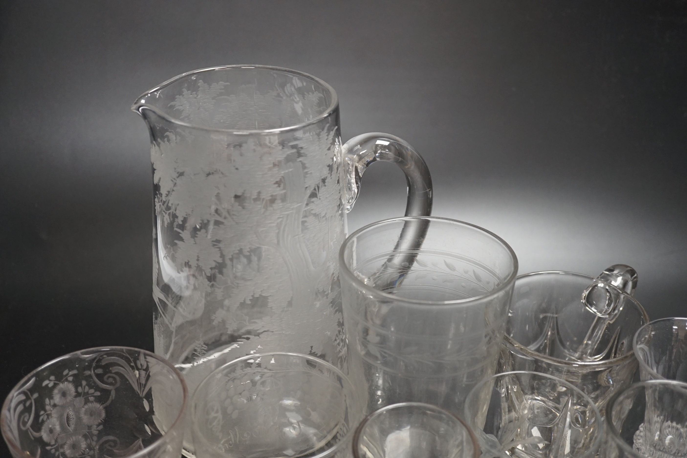 Fourteen 19th century glass items, including a jug heavily engraved with a scene of a stag in a woodland glade, an engraved Sunderland Bridge tumbler, together with another three engraved tumblers, plus some smaller brea